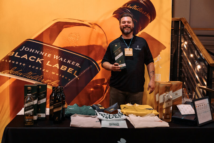 Vendor representatives smiling behind their tasting table display
