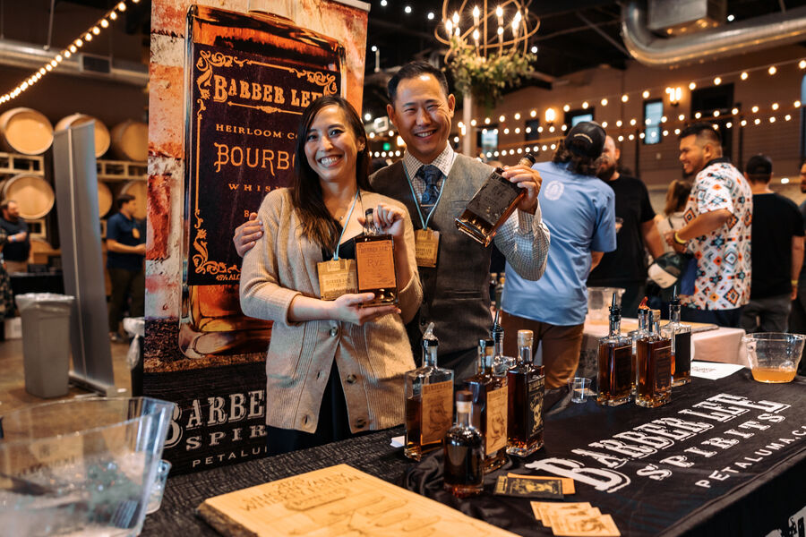Attendees discussing and sampling whisk(e)y at a festival tasting table