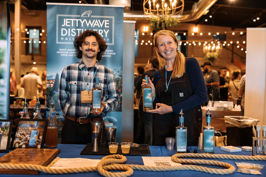 A distiller in a suit and hat explaining whisk(e)y to festival attendees